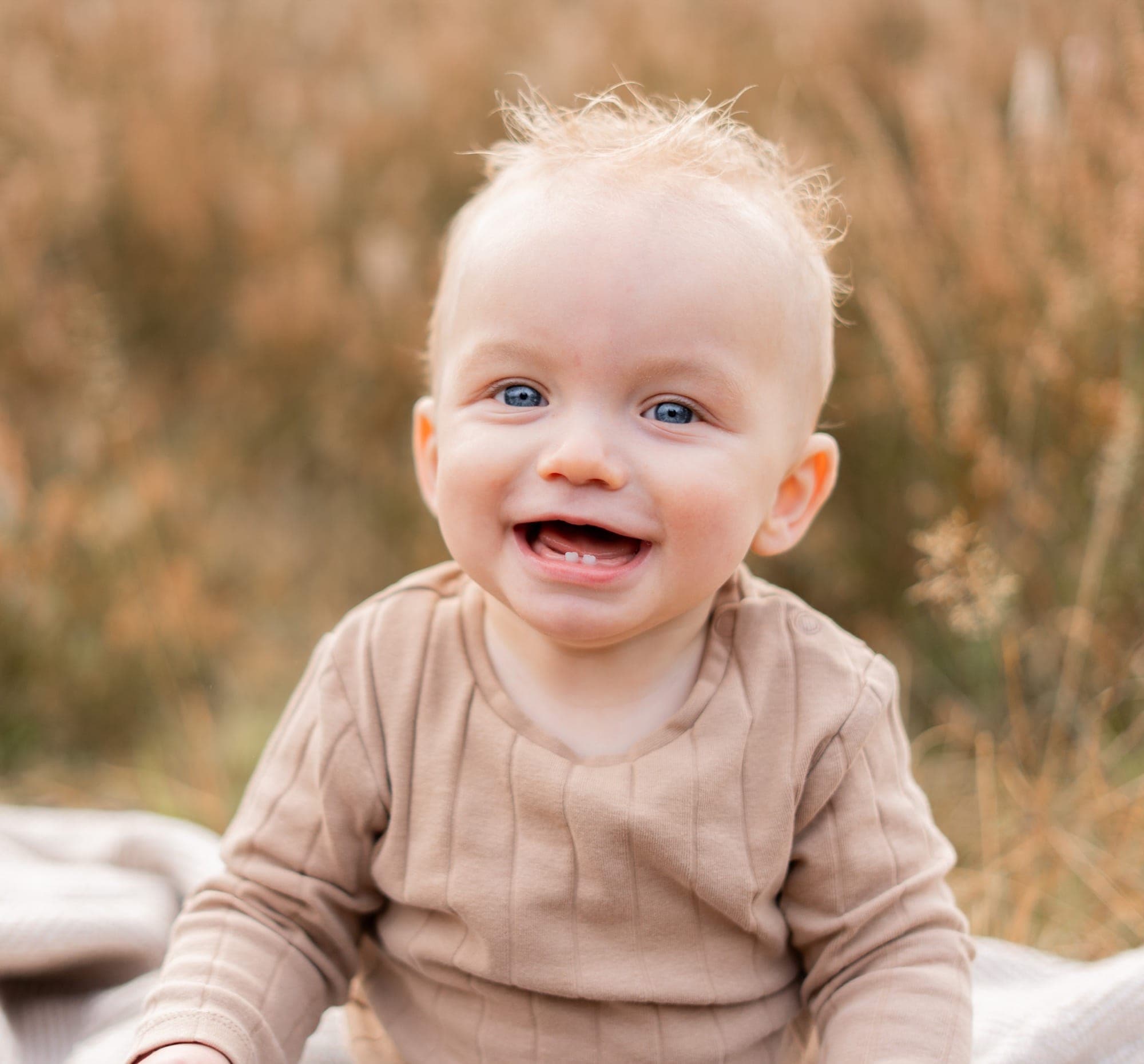 Lachende baby met blauwe ogen in herfstig gras