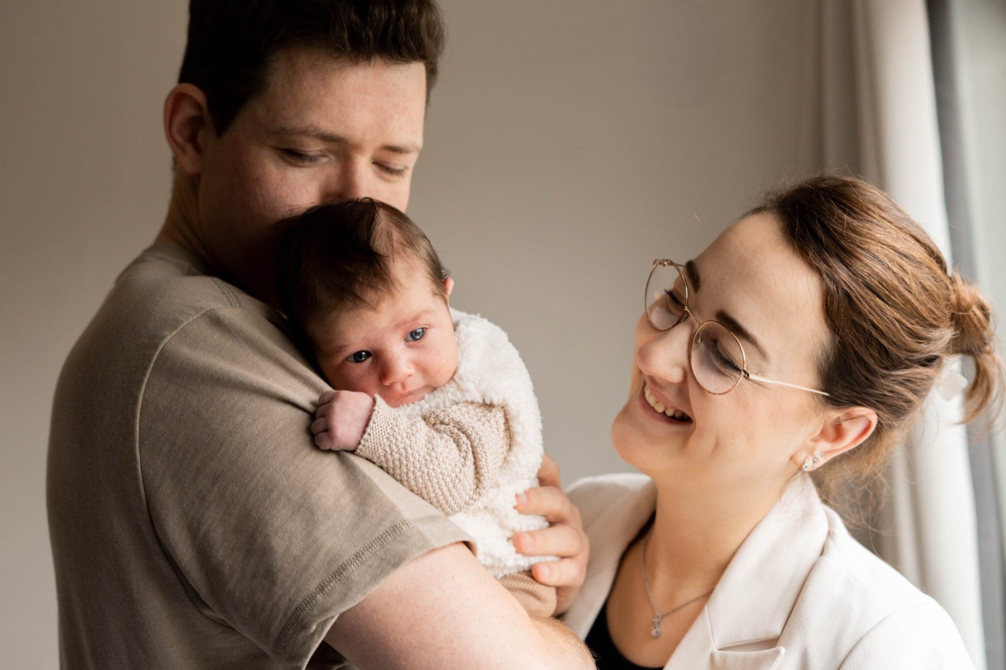 Vader en moeder met hun newborn dicht bij het raam