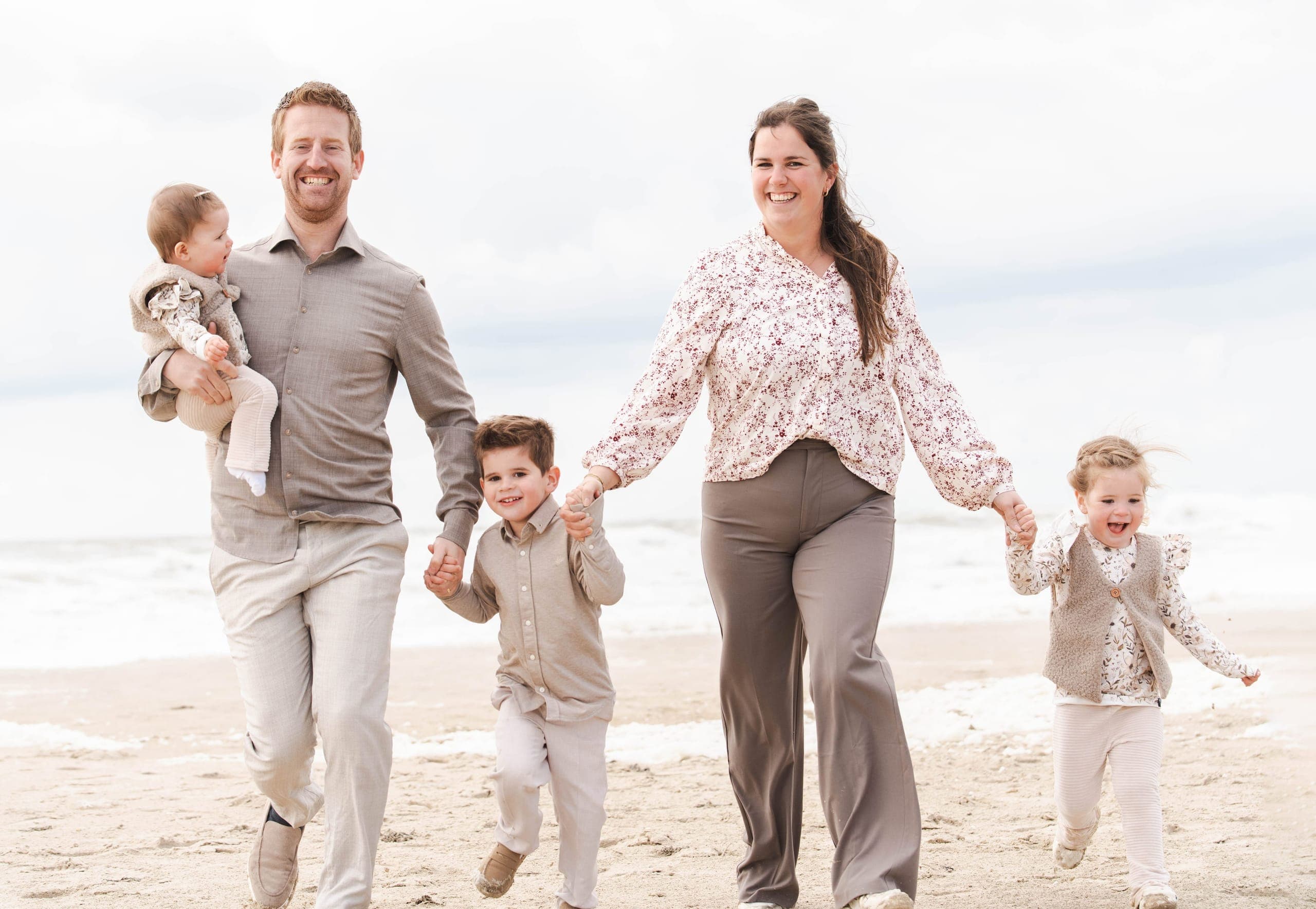 Gezin wandelt hand in hand over het strand